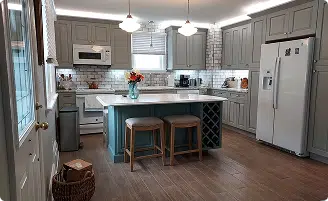Modern kitchen remodeling in Baltimore, MD featuring gray shaker cabinets, a white subway tile backsplash, and a custom teal island with built-in wine storage.