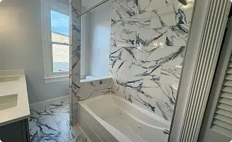 Modern bathroom renovation featuring marble wall tiling and a soaking tub by a professional kitchen and bathroom remodeler in Baltimore, MD.