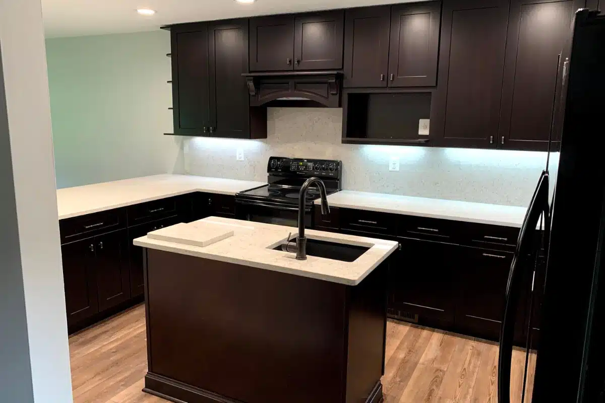 Custom cabinetry in Baltimore, MD showcased in a remodeled kitchen featuring dark wood cabinets, a compact island with integrated sink, and matching countertops.