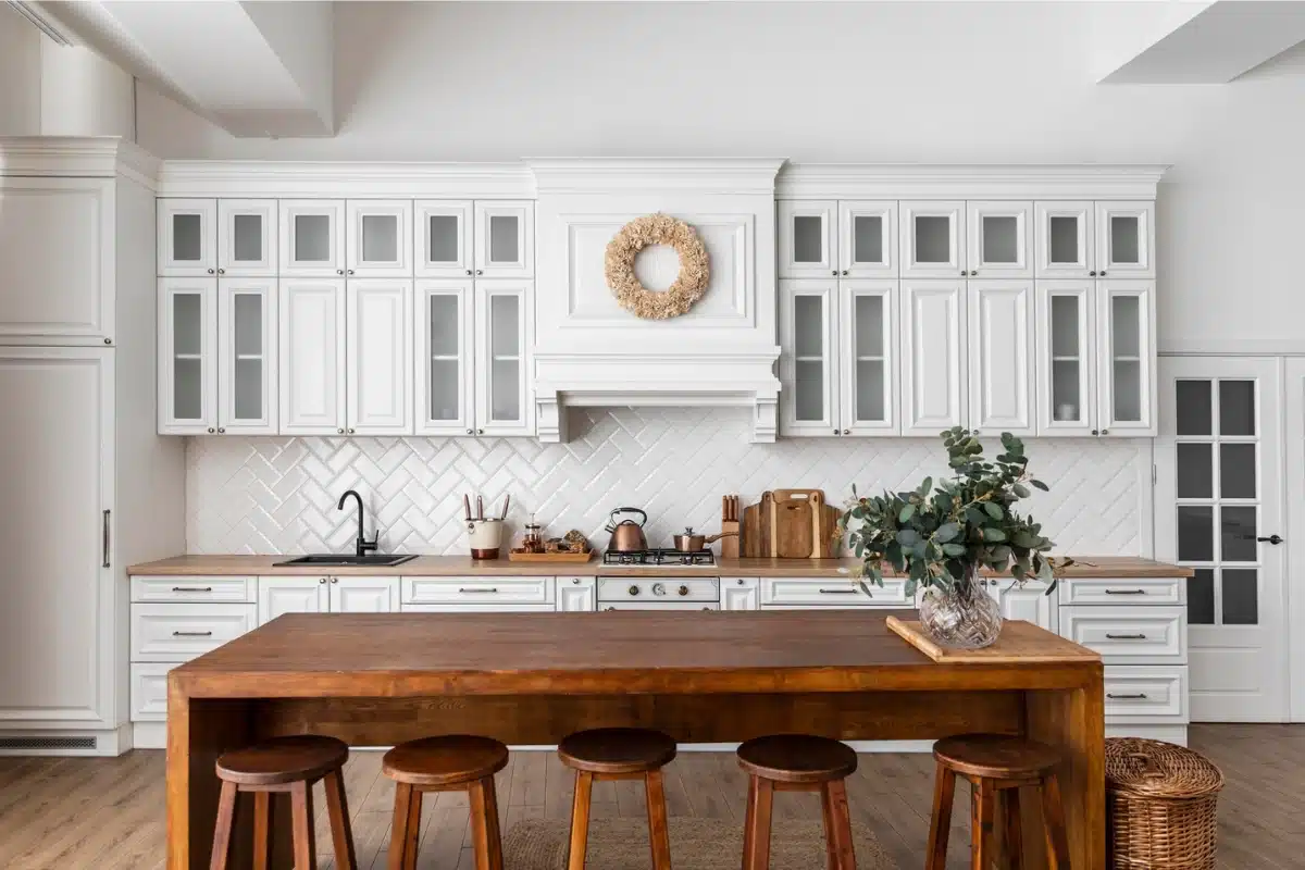 Custom kitchen design in Baltimore MD featuring white cabinetry, wood countertops, herringbone backsplash, and a large rustic dining island.