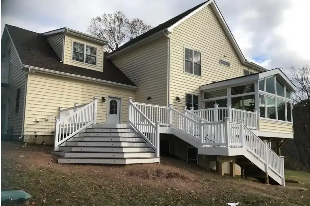 Custom deck building in Baltimore, MD featuring a multi-level white railing deck and stairs connected to a remodeled home exterior.