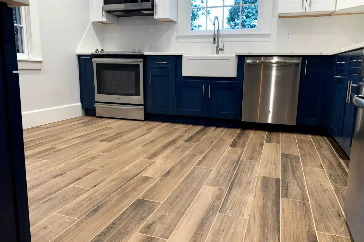Professional flooring installation in Baltimore, MD featuring wood-look tile flooring in a newly remodeled kitchen with modern cabinets and appliances.