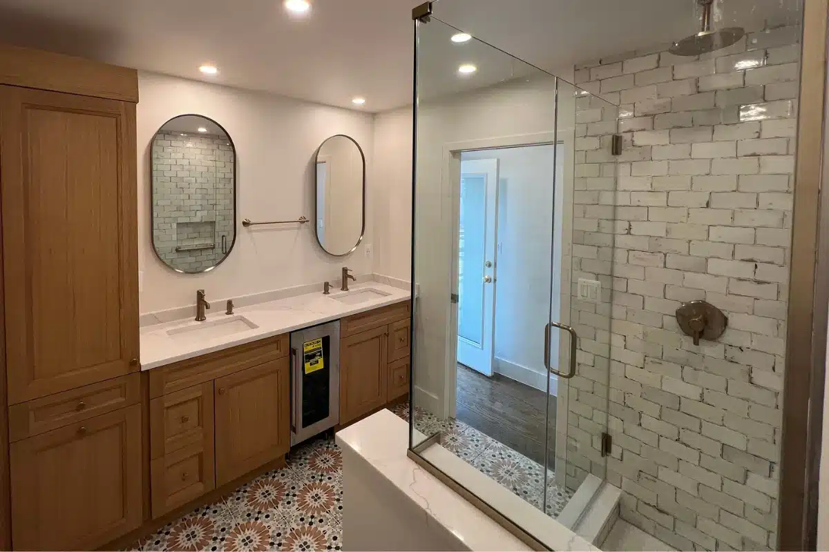 Alt Text Modern bathroom with clear glass shower doors and wood cabinetry, illustrating professional glass shower door installation services in Baltimore, MD.