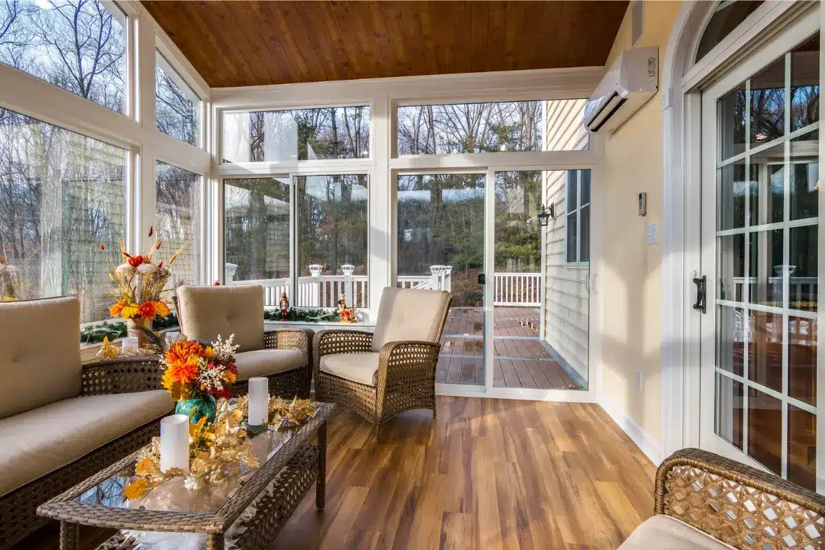 Home remodeling in Baltimore, MD showcased through a bright sunroom renovation with large windows, wood ceiling, updated flooring, and comfortable seating.