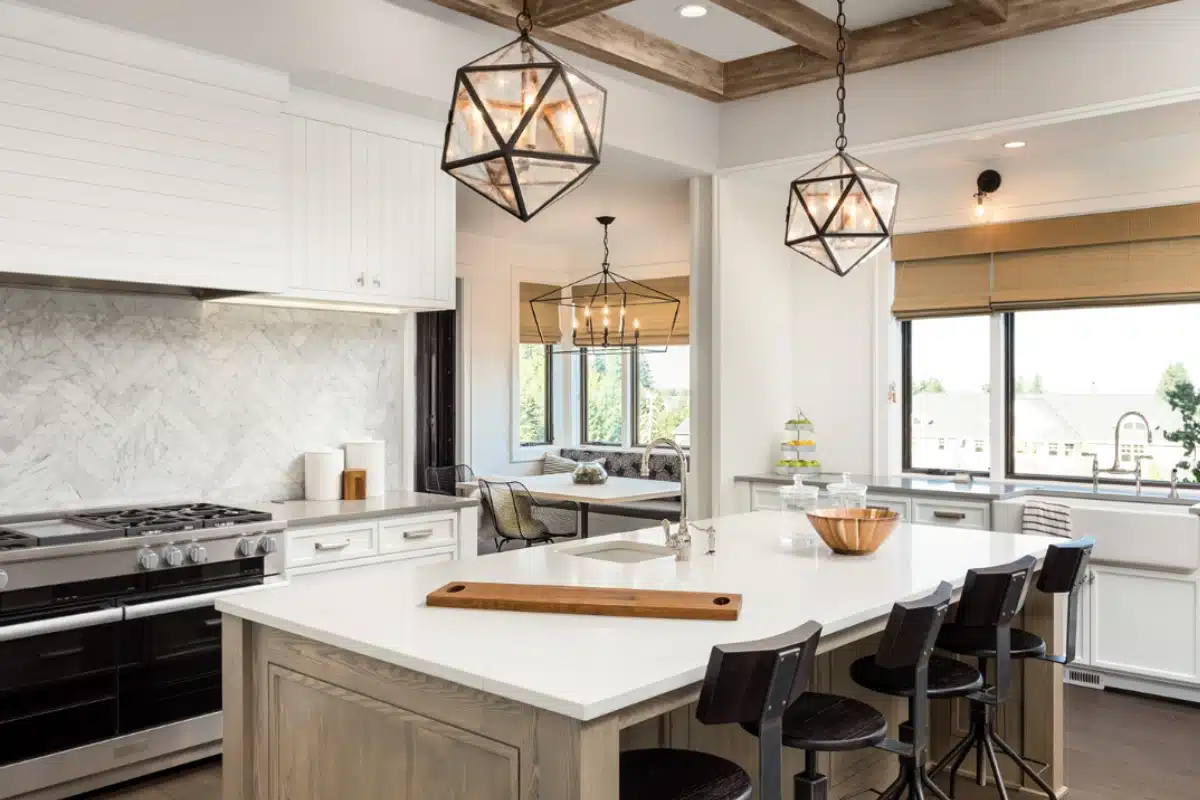 Kitchen lighting installation in Baltimore, MD featuring modern geometric pendant lights illuminating a bright, remodeled kitchen with a large island, wood accents, and open dining space.