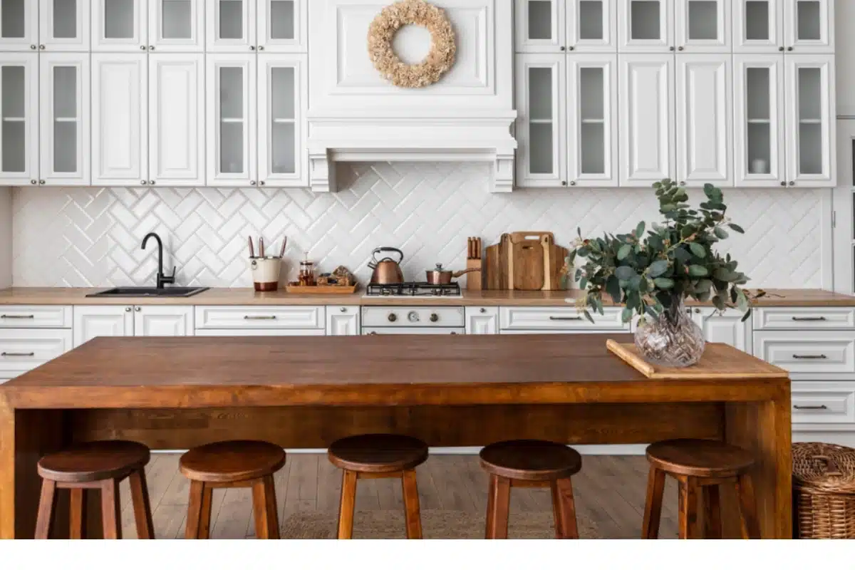 Modern kitchen remodel in Baltimore MD featuring white shaker cabinets, herringbone tile backsplash, wood dining island, and warm natural lighting.