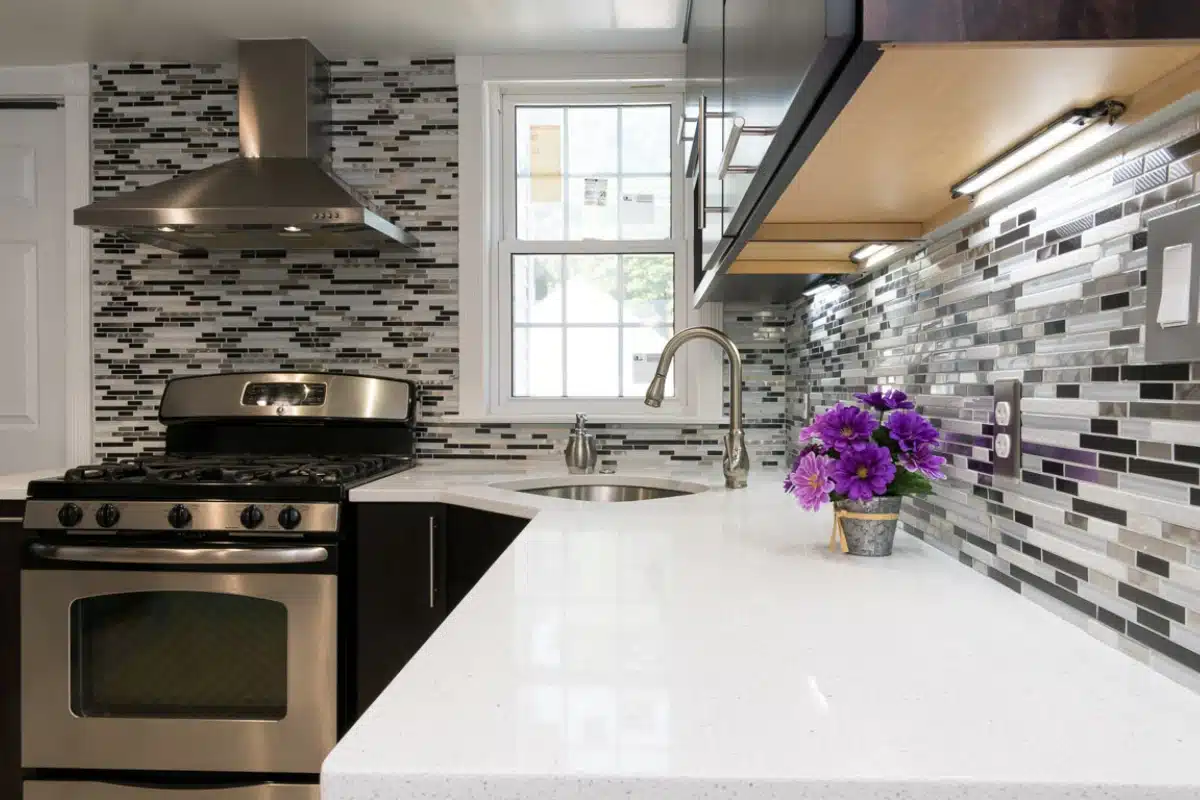 Modern kitchen sink installation in Baltimore, MD featuring an undermount sink, sleek faucet, stainless steel appliances, and a stylish mosaic tile backsplash.