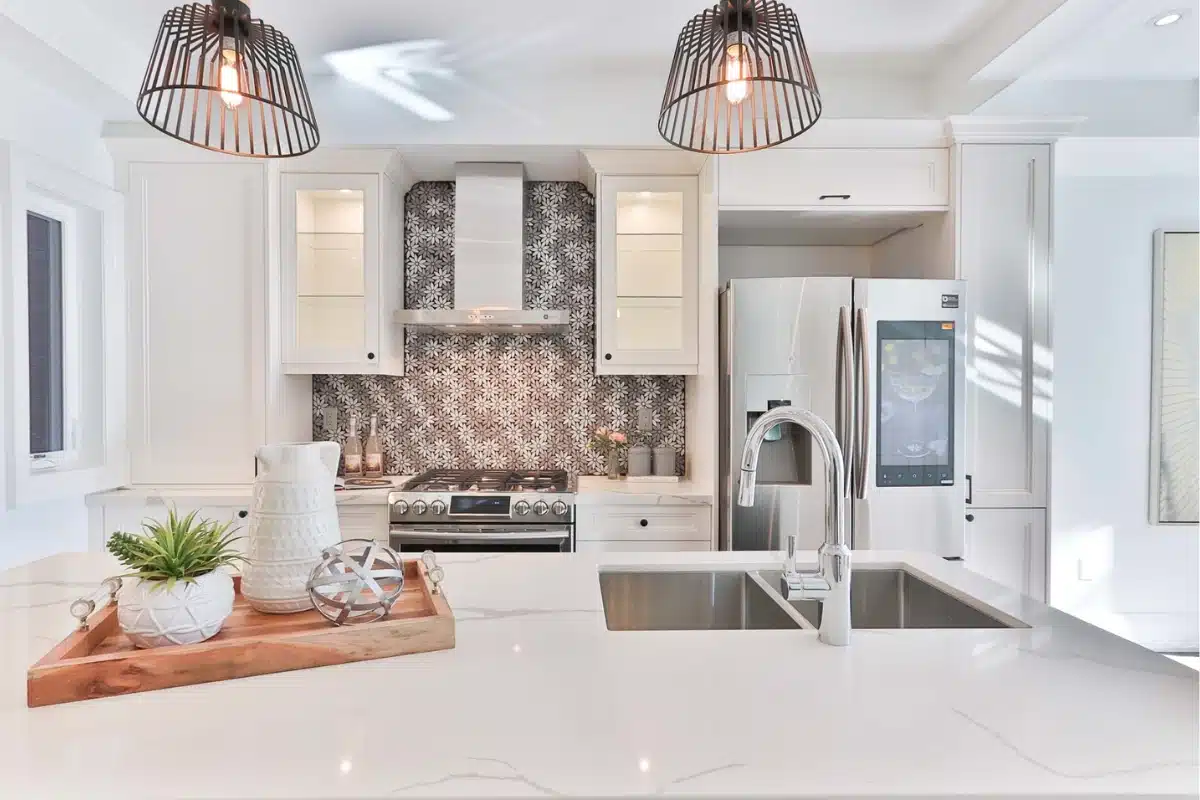 Modern small kitchen remodel in Baltimore MD featuring white cabinets, patterned backsplash, stainless steel appliances, and a sleek quartz island.