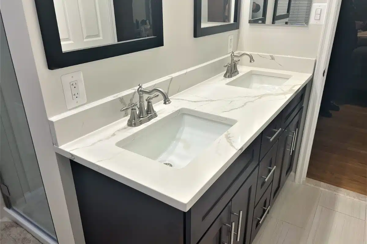 Modern double-sink vanity installation in Baltimore, MD featuring dark cabinetry, marble-style countertops, and updated fixtures.