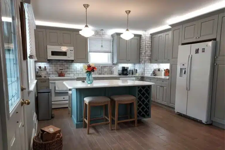 Modern kitchen remodeling in Baltimore, MD featuring gray shaker cabinets, white subway tile backsplash, and a custom island with seating.