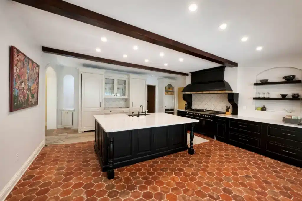 High-end kitchen remodeling in Baltimore, MD with a large custom island, contrasting cabinetry, exposed ceiling beams, and designer lighting.