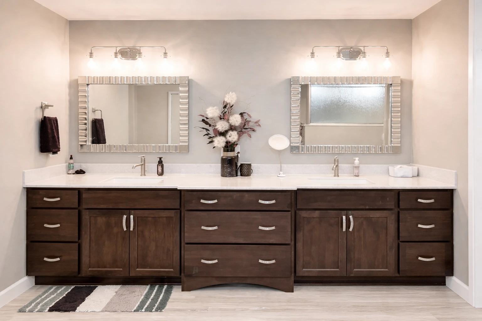 Custom bathroom remodeling in Baltimore, MD with a wide double vanity, rich wood cabinetry, decorative mirrors, and modern vanity lighting.