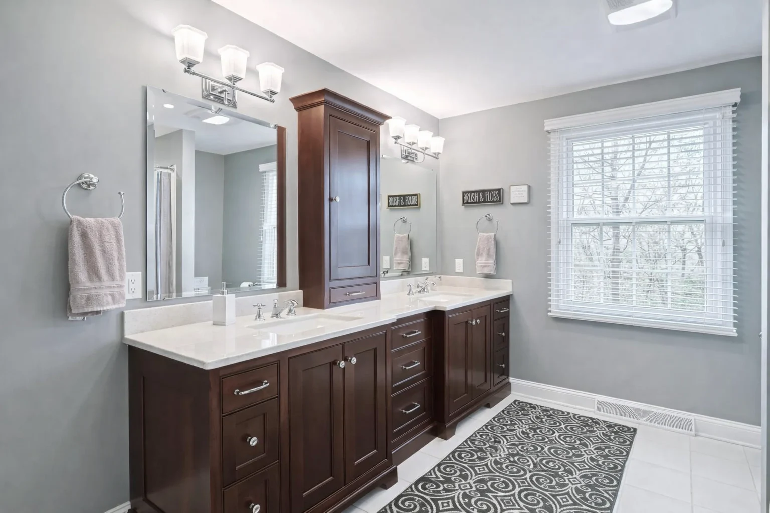 Bathroom remodeling project in Baltimore, MD featuring a double vanity with integrated storage cabinet, quartz countertops, and contemporary lighting.