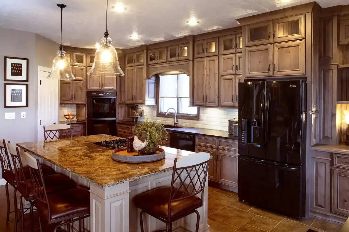 Traditional kitchen remodeling project with rustic wood cabinets, large stone island, pendant lighting, and black appliances in Four By Four, Baltimore