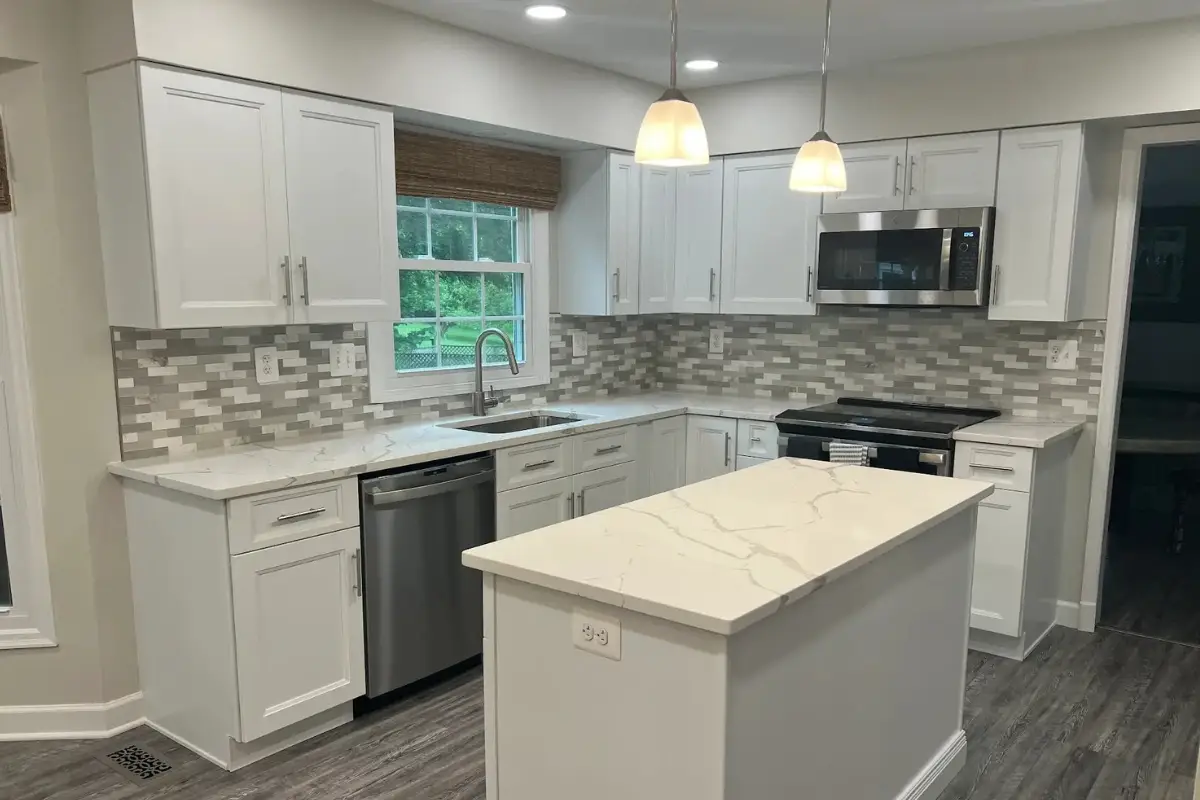 Kitchen remodeling project in Frankford, Baltimore featuring white shaker cabinets, a marble-look island, pendant lighting, and a decorative tile backsplash.
